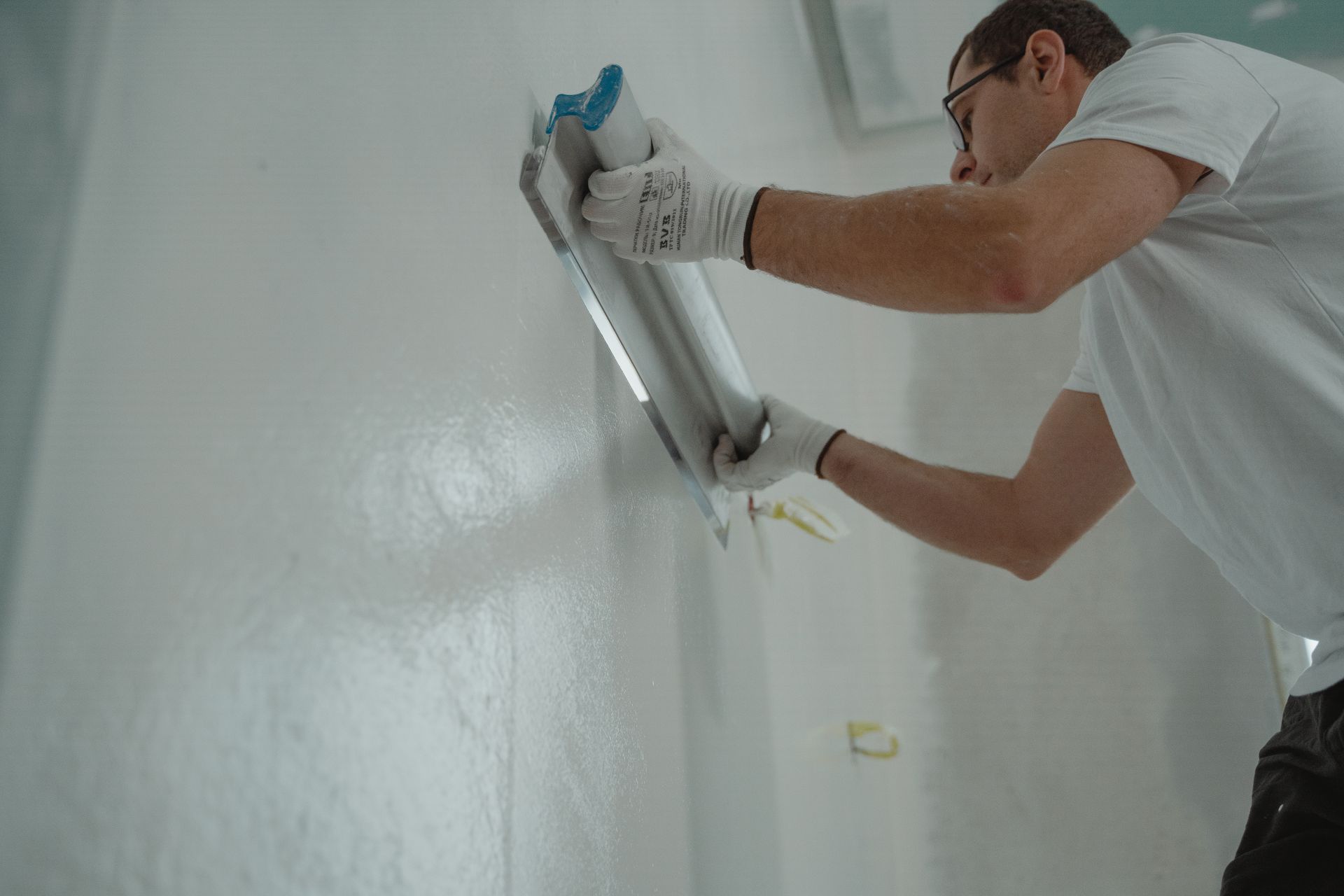 Handwerker bearbeitet eine weisse Innenwand