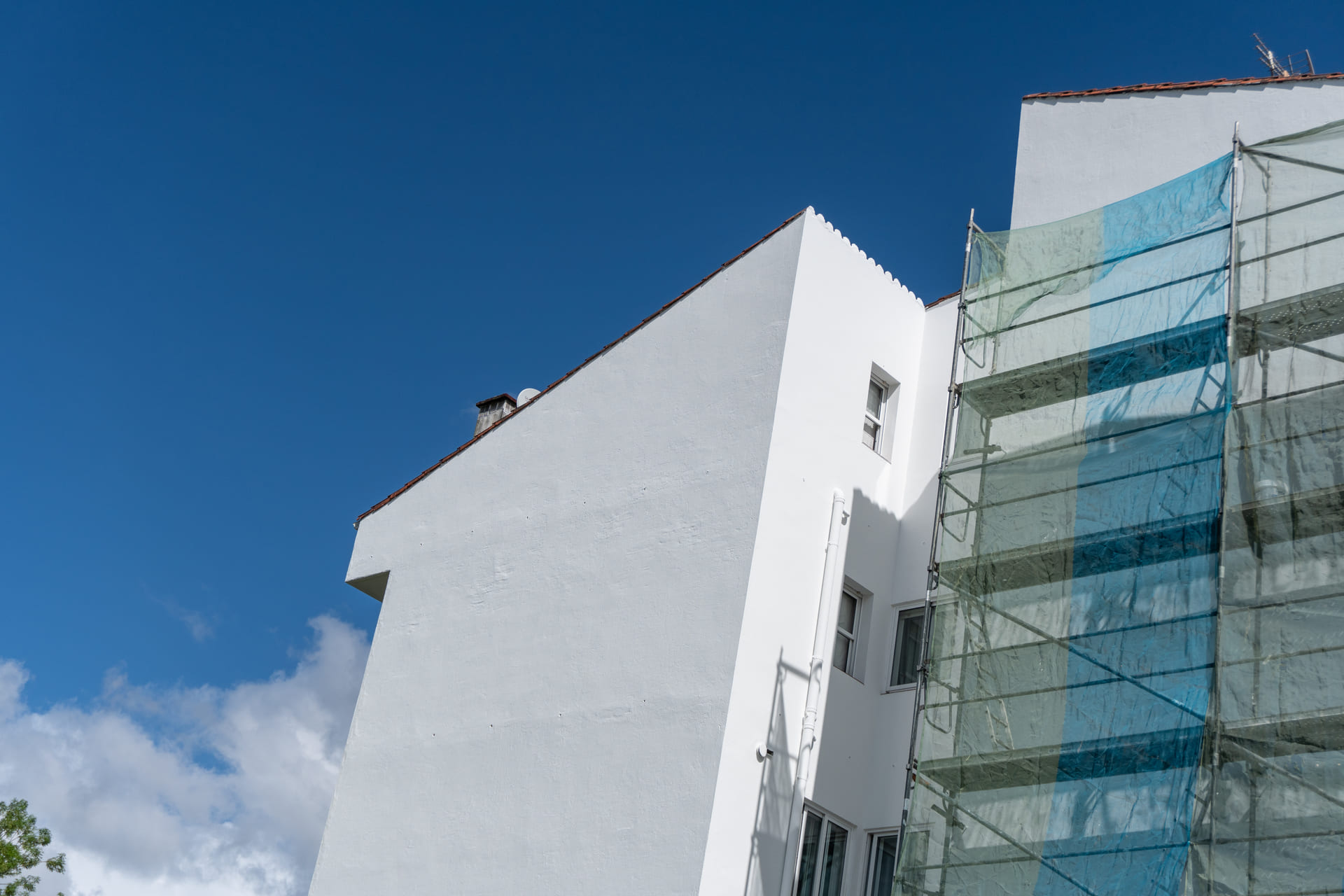 Frisch verputzte, weisse Hausfassade vor blauem Himmel